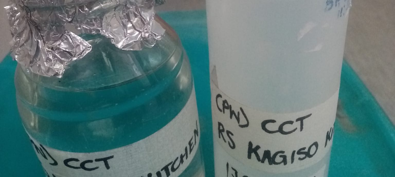 Water testing samples from kitchen taps in small bottles.